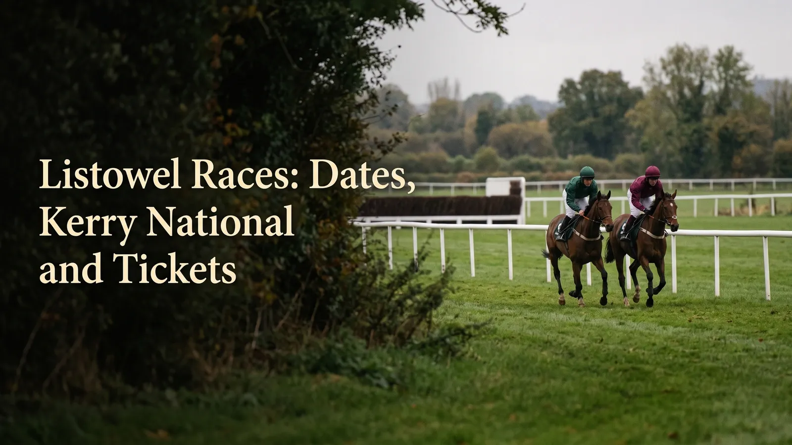 Two brown racehorses with jockeys in green and burgundy run across grass beside white rails, with a brush jump and trees behind them.
